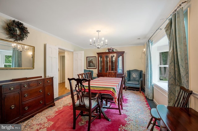 dining space with crown molding, light hardwood / wood-style floors, and a chandelier