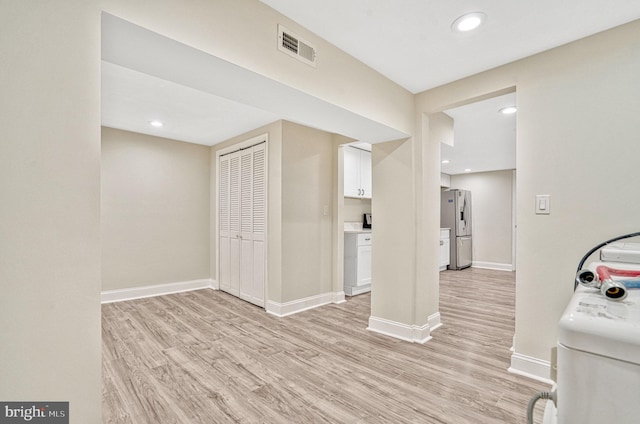 interior space featuring stainless steel fridge with ice dispenser and light hardwood / wood-style flooring