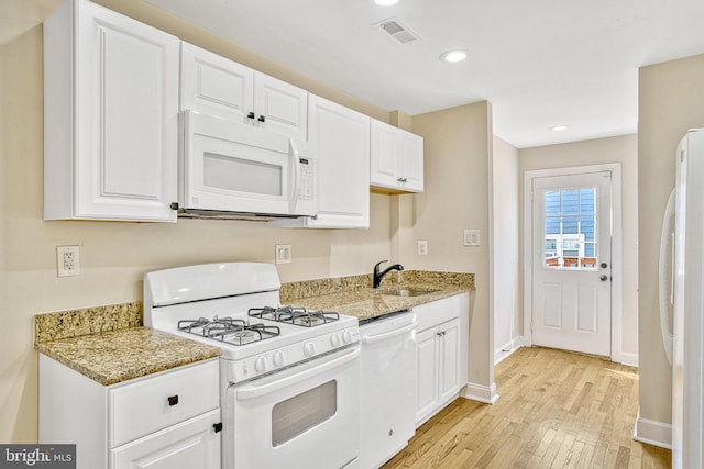 kitchen with white cabinets, white appliances, light stone countertops, light hardwood / wood-style floors, and sink