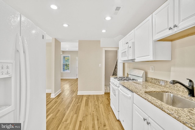 kitchen with white appliances, light stone counters, light hardwood / wood-style floors, white cabinetry, and sink