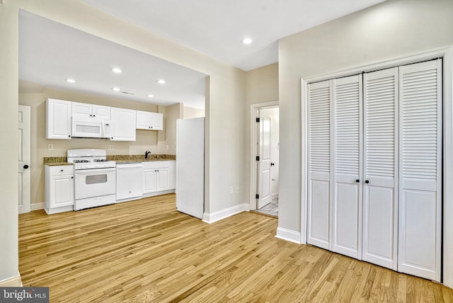 kitchen with light wood-type flooring, white cabinets, white appliances, and sink