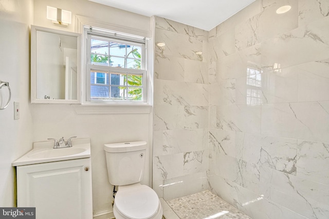 bathroom featuring tiled shower, vanity, and toilet