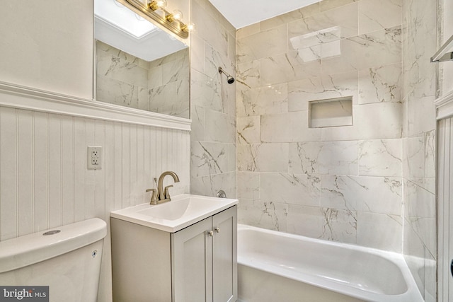 full bathroom featuring tiled shower / bath, vanity, and toilet