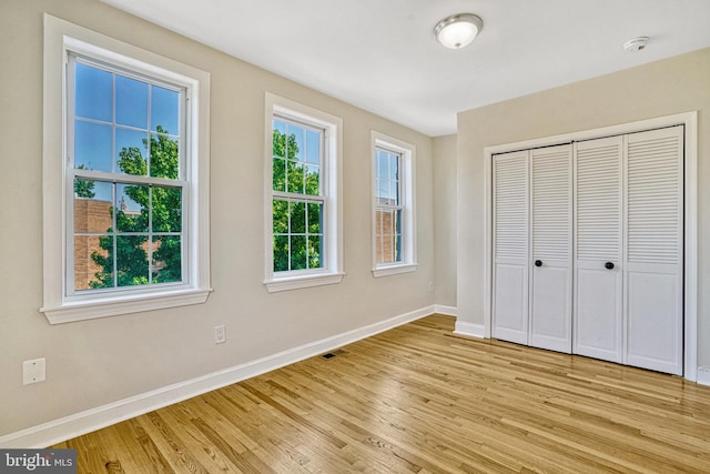 unfurnished bedroom with a closet and light wood-type flooring