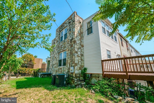 view of side of property with a yard, a wooden deck, and central AC