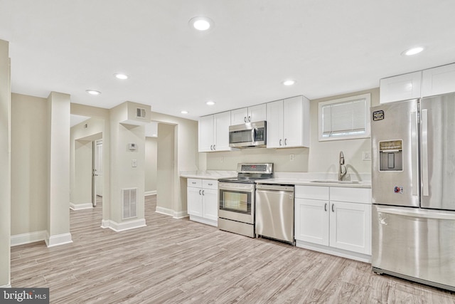 kitchen featuring stainless steel appliances, sink, and white cabinetry