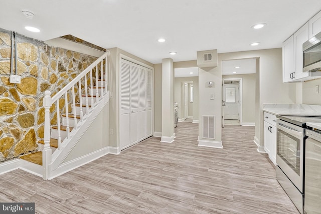 kitchen with light wood-type flooring, appliances with stainless steel finishes, and white cabinetry