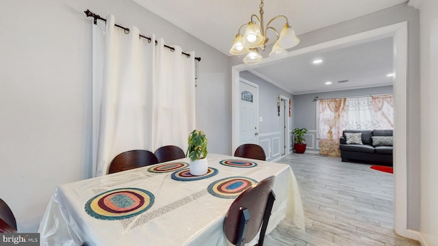 dining room featuring an inviting chandelier, light hardwood / wood-style flooring, and ornamental molding