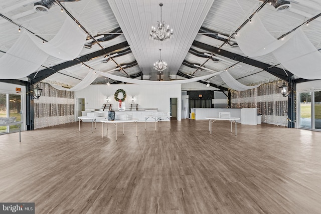 unfurnished living room featuring an inviting chandelier, high vaulted ceiling, and wood-type flooring