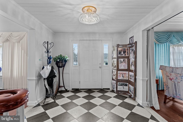 tiled entrance foyer with crown molding and a chandelier