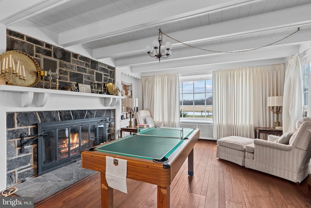 game room with beamed ceiling, pool table, a stone fireplace, and hardwood / wood-style floors