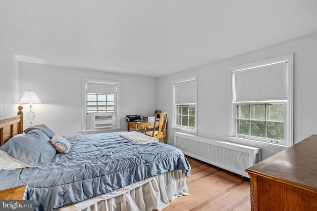 bedroom with radiator, cooling unit, and hardwood / wood-style floors