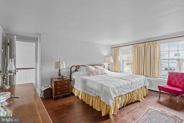 bedroom with dark wood-type flooring and radiator heating unit