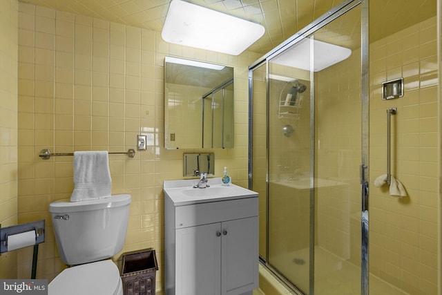 bathroom featuring vanity, toilet, an enclosed shower, and tile walls