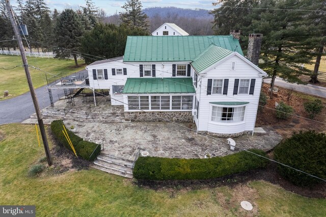 back of property featuring a sunroom and a lawn