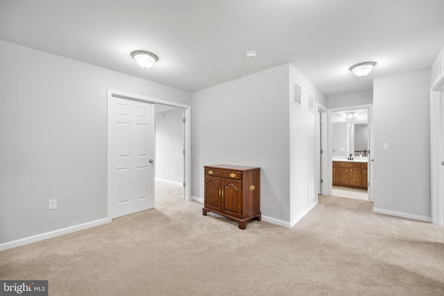 unfurnished bedroom featuring connected bathroom and light colored carpet