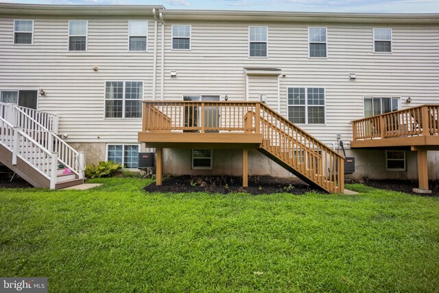 back of property with a wooden deck and a lawn