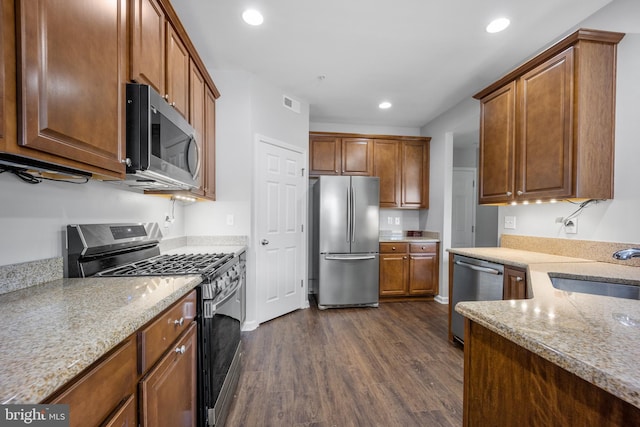 kitchen with sink, dark hardwood / wood-style flooring, stainless steel appliances, and light stone countertops