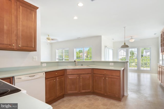 kitchen featuring white dishwasher, sink, decorative light fixtures, and kitchen peninsula