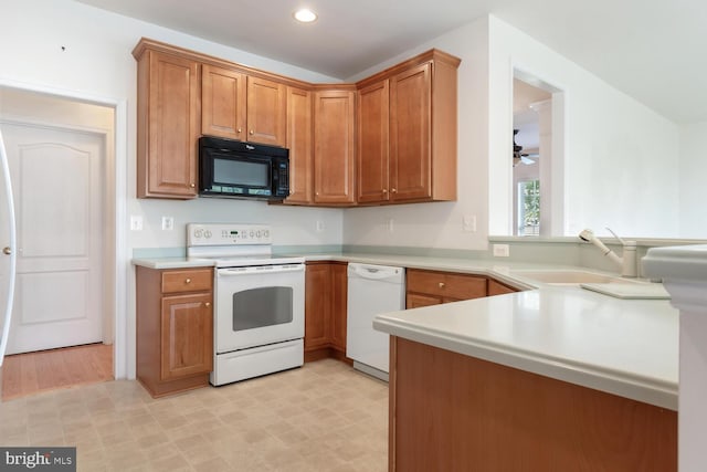 kitchen with white appliances, kitchen peninsula, and sink