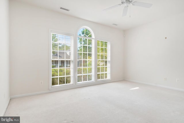 carpeted spare room featuring a healthy amount of sunlight and ceiling fan