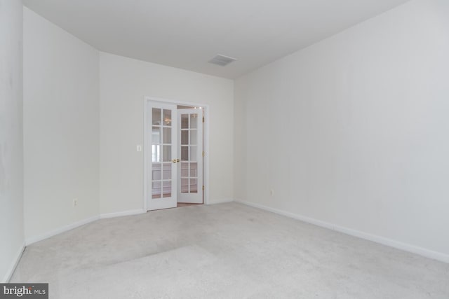 empty room featuring light carpet and french doors