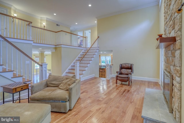 living room featuring ornamental molding, light wood finished floors, stairs, and a high ceiling