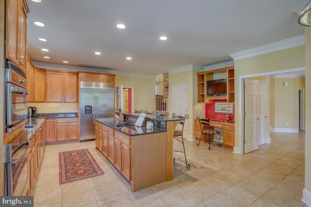 kitchen with dark stone counters, ornamental molding, a kitchen breakfast bar, an island with sink, and stainless steel appliances