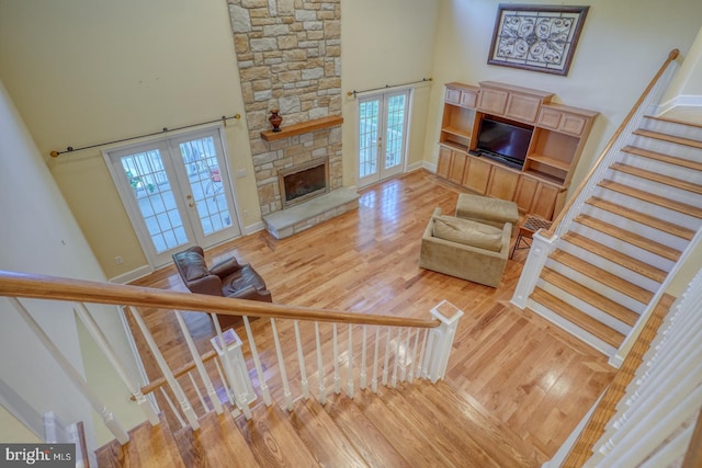 living room featuring a towering ceiling, stairway, wood finished floors, and french doors