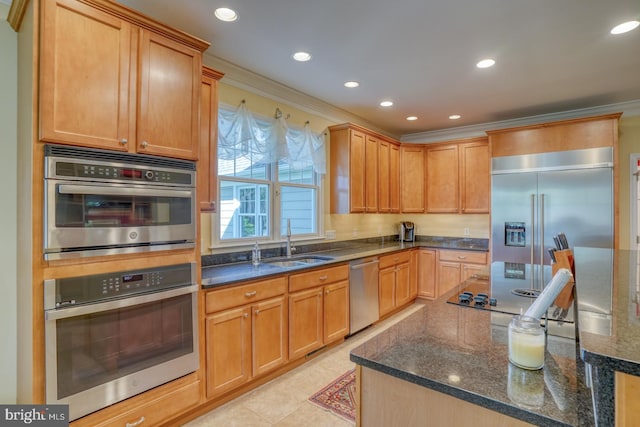 kitchen with sink, crown molding, stainless steel appliances, and dark stone counters