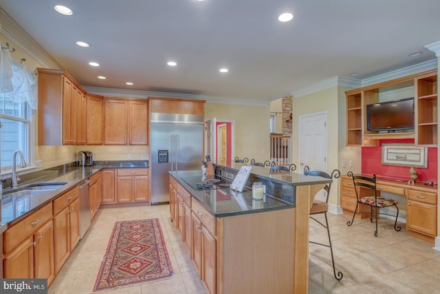 kitchen featuring stainless steel appliances, ornamental molding, a sink, a kitchen island, and a kitchen breakfast bar