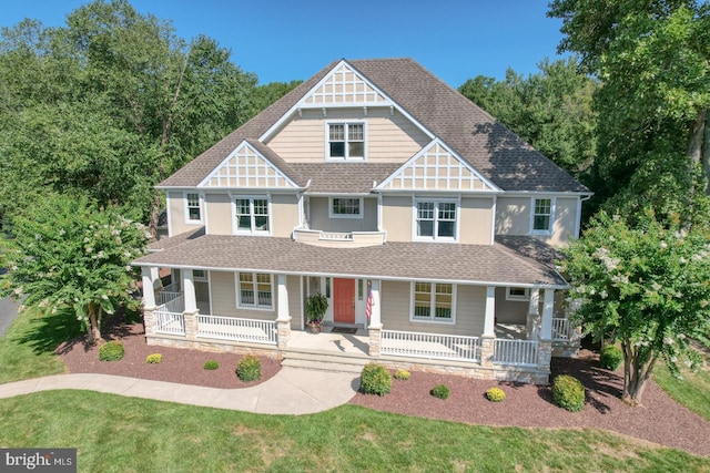 view of front of home featuring a porch, a shingled roof, and a front lawn