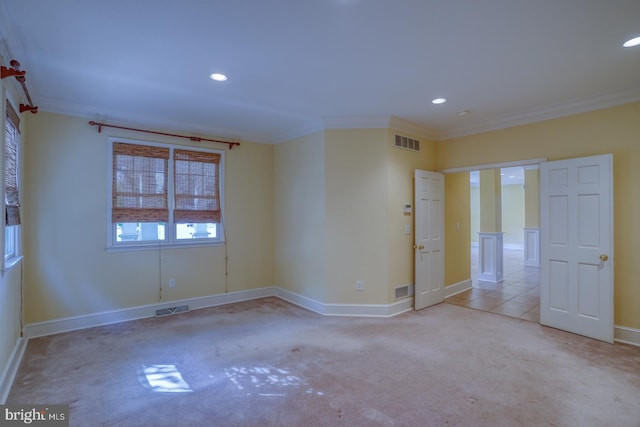 unfurnished room with light colored carpet, visible vents, crown molding, and baseboards