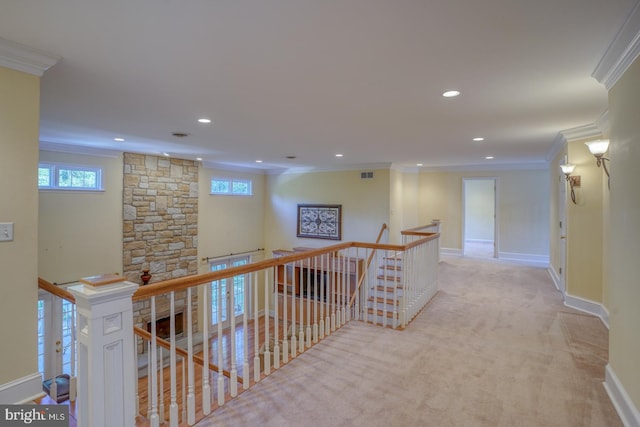 hallway featuring light carpet, visible vents, baseboards, ornamental molding, and an upstairs landing