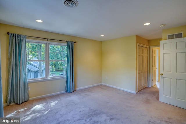 spare room with light carpet, visible vents, and baseboards