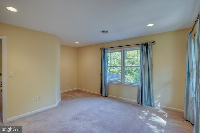 spare room featuring recessed lighting, light colored carpet, and baseboards