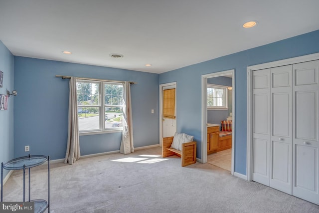 unfurnished bedroom featuring visible vents, multiple windows, baseboards, and light colored carpet