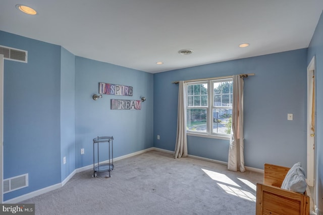 interior space with baseboards, visible vents, and light colored carpet