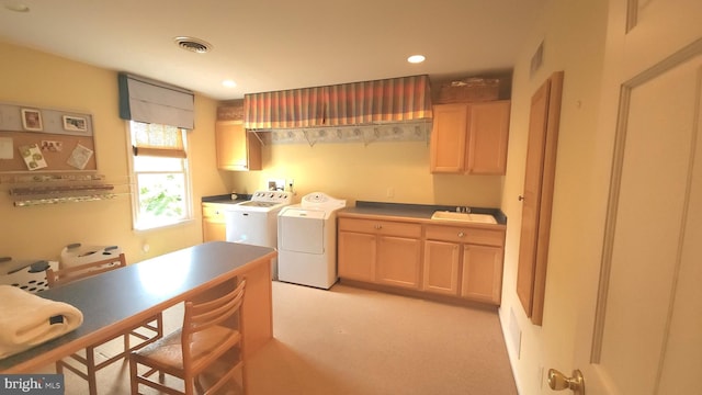 kitchen with visible vents, washer and clothes dryer, a sink, and light brown cabinetry