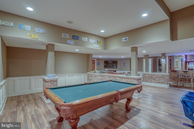 recreation room featuring recessed lighting, visible vents, a decorative wall, light wood-style floors, and wainscoting