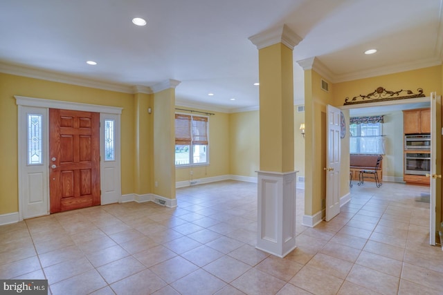 entryway with light tile patterned floors, crown molding, and decorative columns