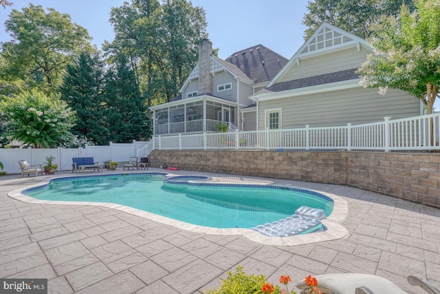 view of pool featuring a patio, a pool with connected hot tub, a fenced backyard, and a sunroom