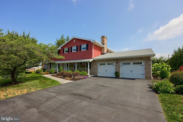 traditional-style house featuring aphalt driveway, brick siding, a chimney, and an attached garage