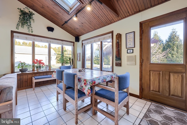 dining room with vaulted ceiling with skylight, wood ceiling, baseboards, and light tile patterned flooring