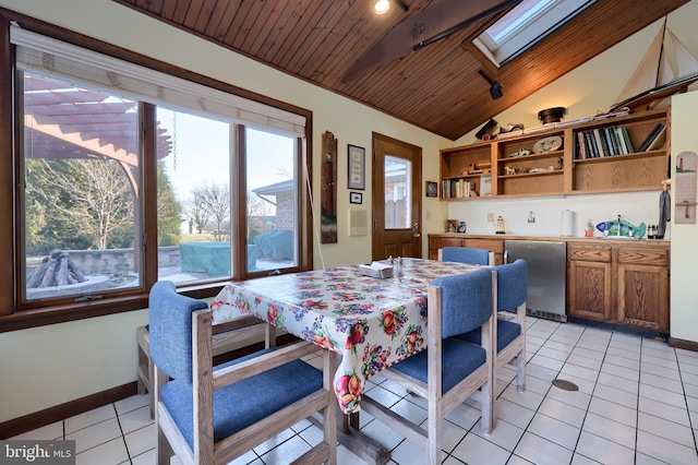 dining space featuring lofted ceiling with skylight, wooden ceiling, light tile patterned flooring, and baseboards