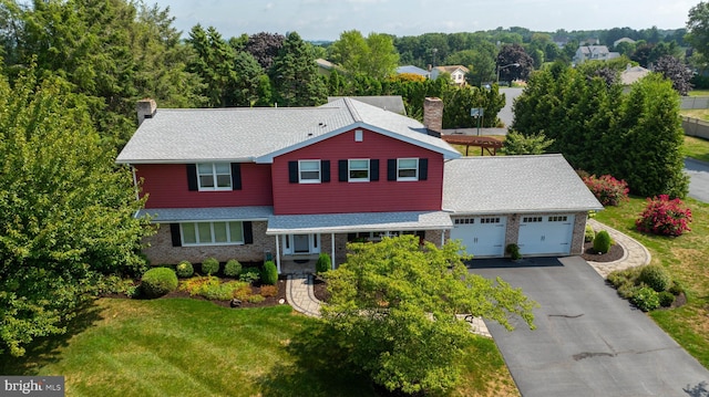 traditional home with a garage, brick siding, driveway, a chimney, and a front yard