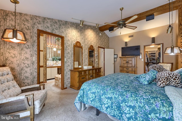 carpeted bedroom with a walk in closet, visible vents, lofted ceiling with beams, ensuite bath, and wallpapered walls