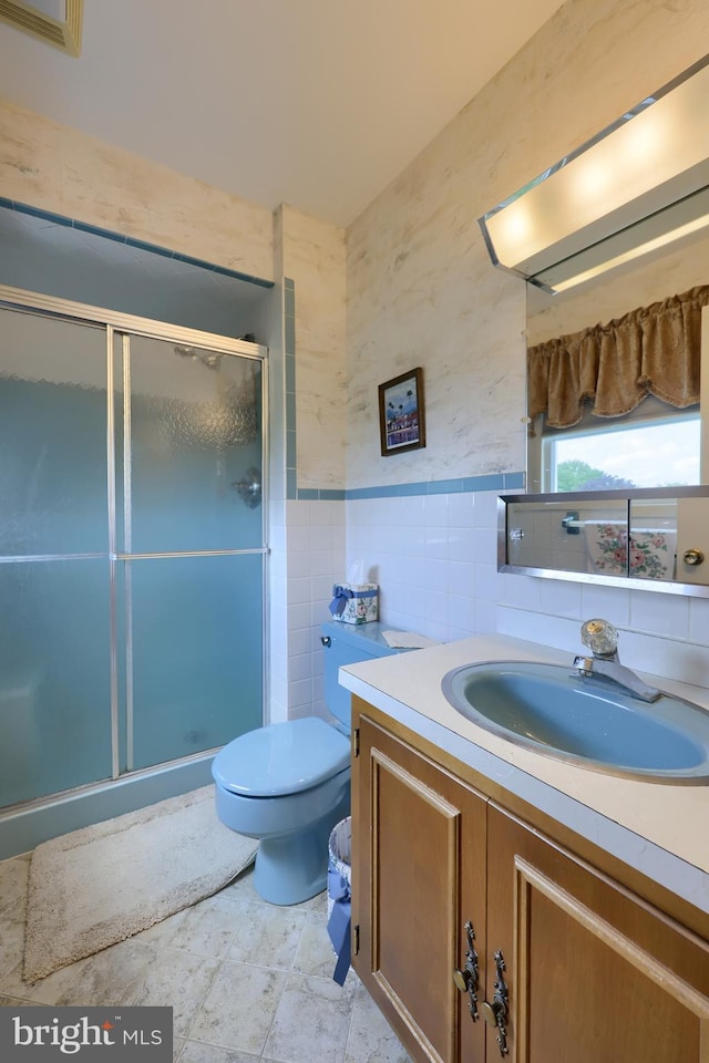 full bath with toilet, a wainscoted wall, vanity, tile walls, and a stall shower