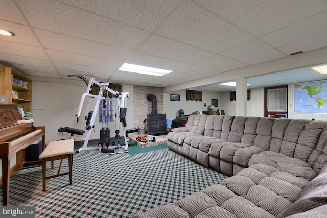 carpeted living room featuring visible vents, a drop ceiling, and a wood stove