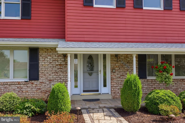 view of exterior entry with a shingled roof